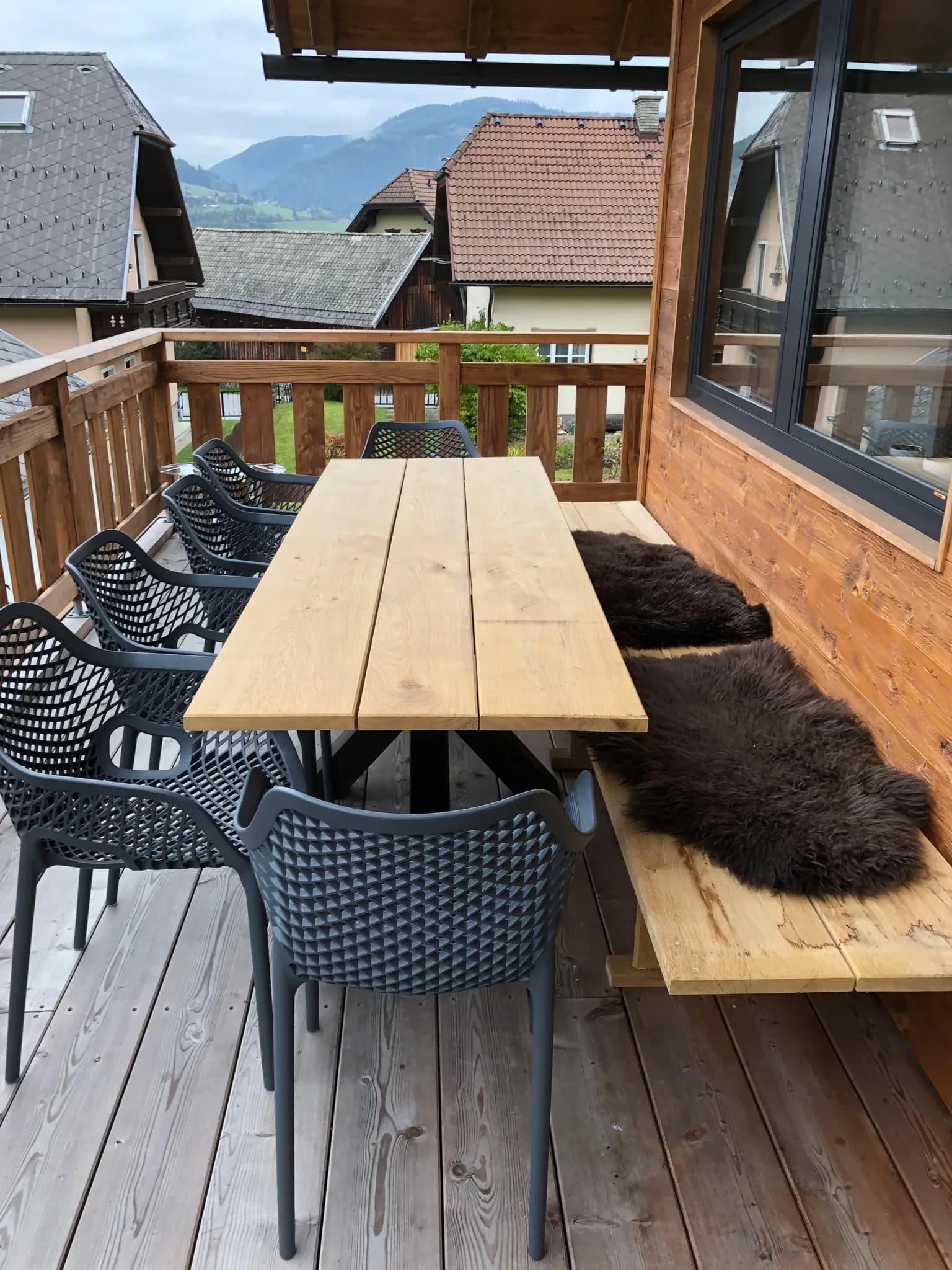 Überdachte Terrasse mit Holztisch und Loungebank
