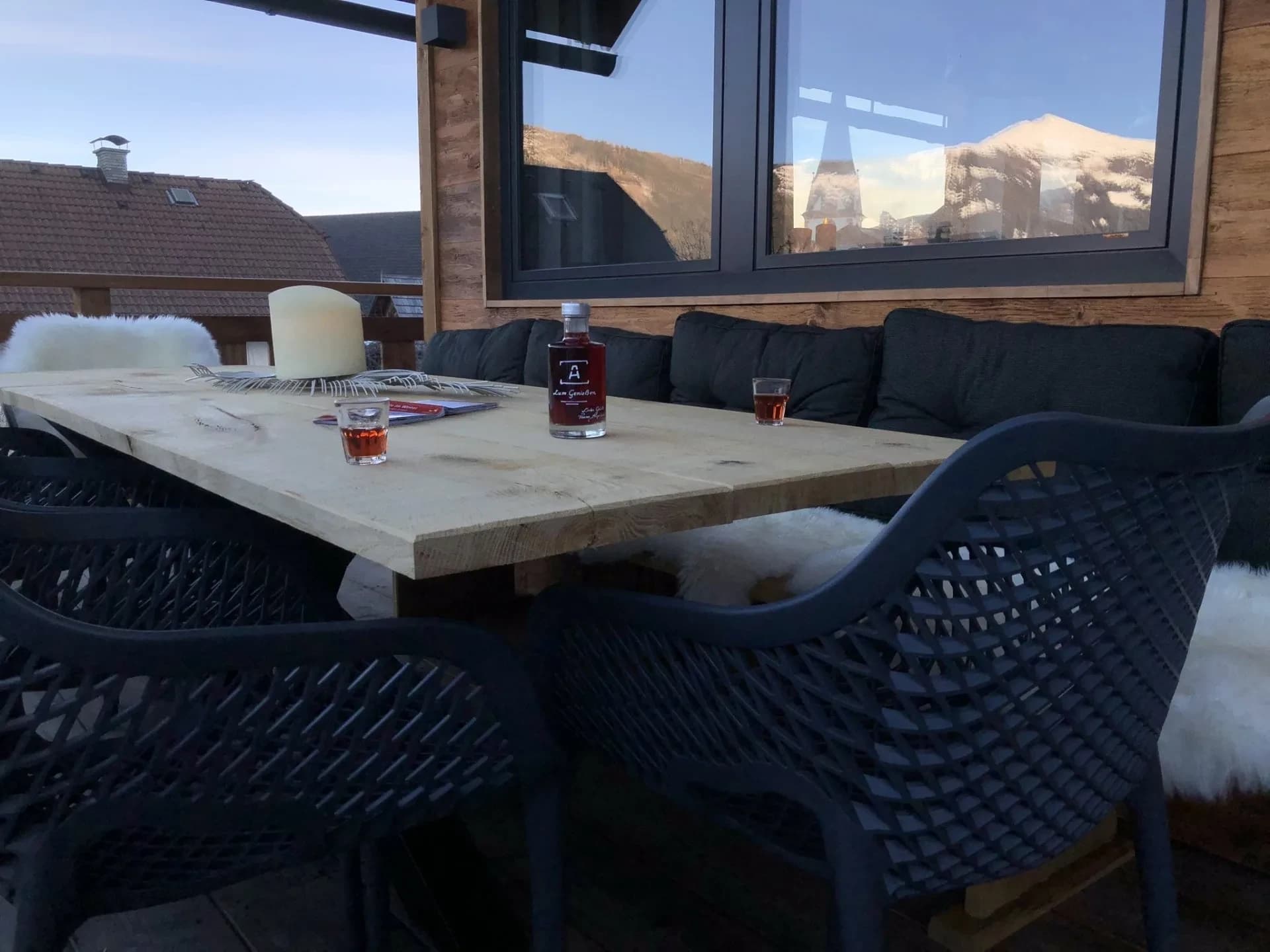 Terrassentisch in der Wintersonne mit Blick auf die verschneiten Berge