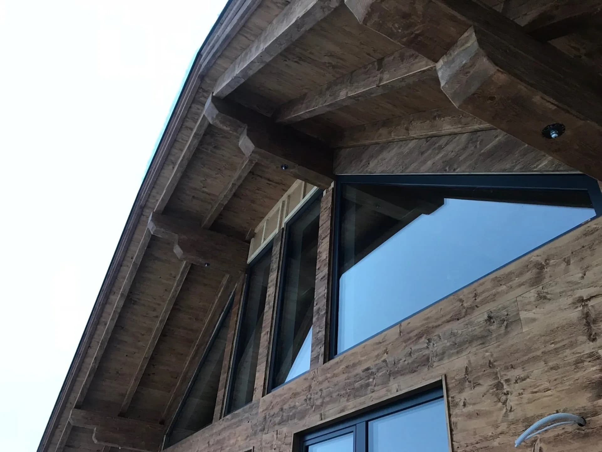 Holzgiebel des Altholz-Chalets vor blauem Himmel