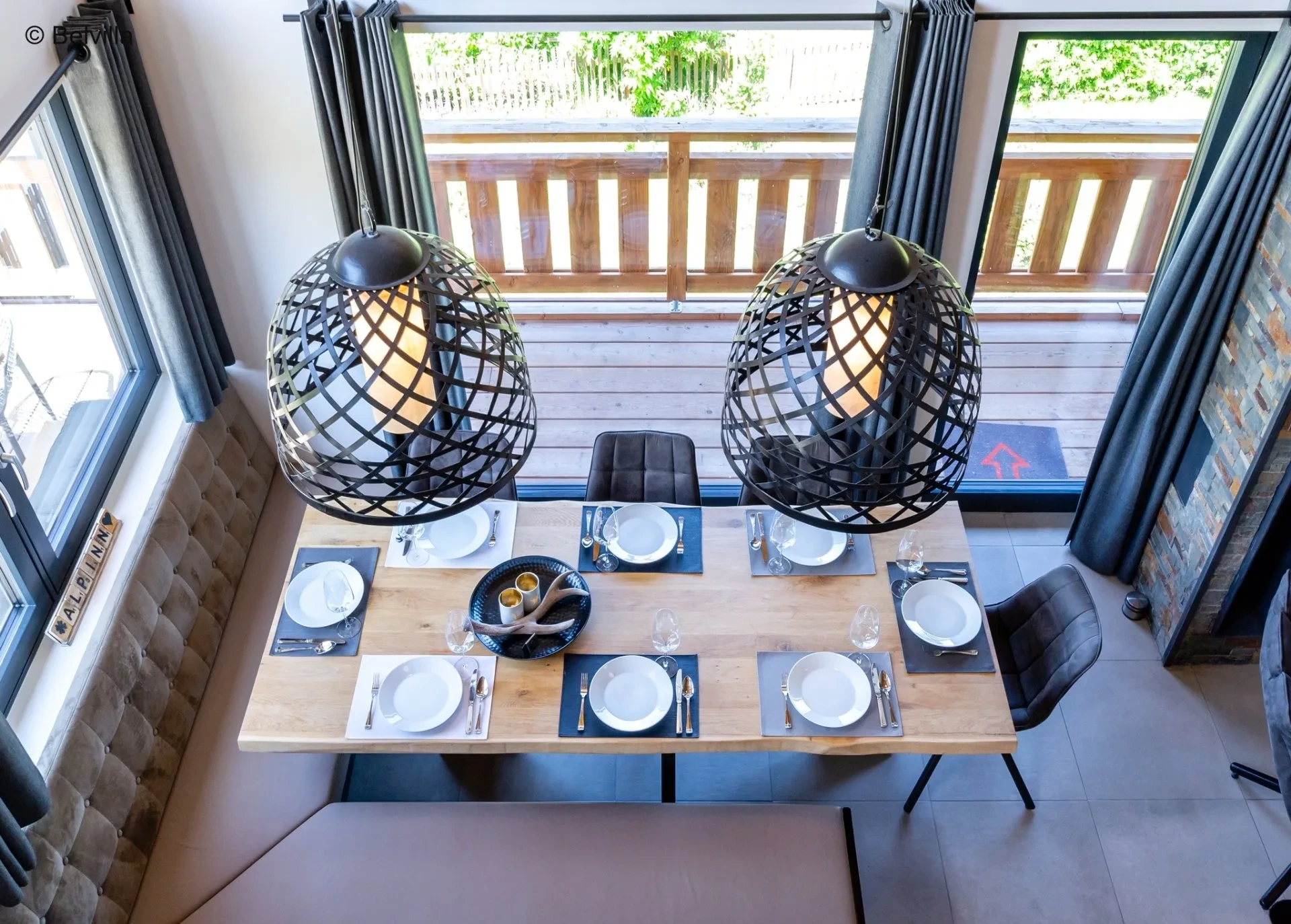 Laid dining table with designer lamps by the window