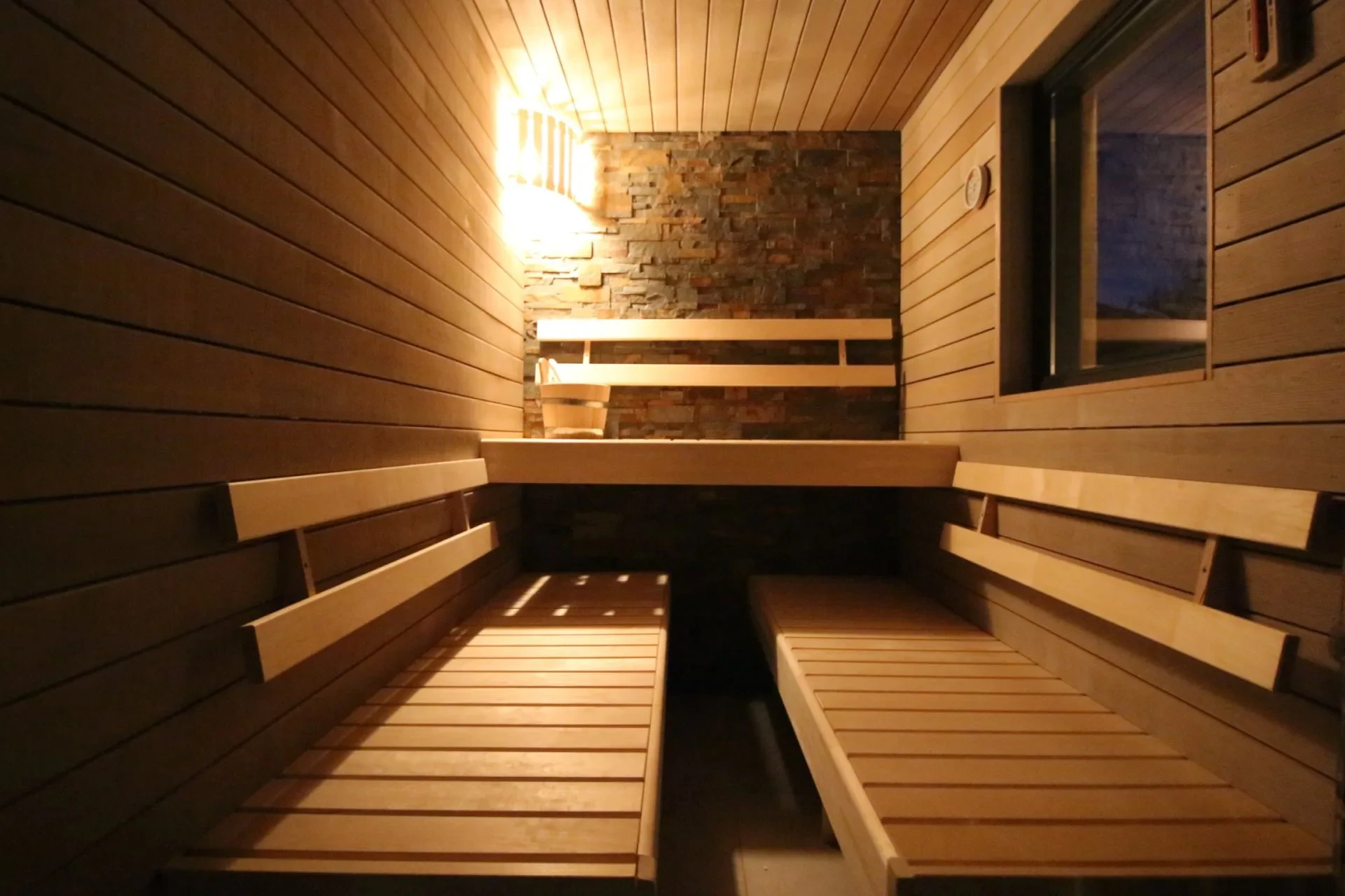 Private Sauna mit Holzbänken und Natursteinwand