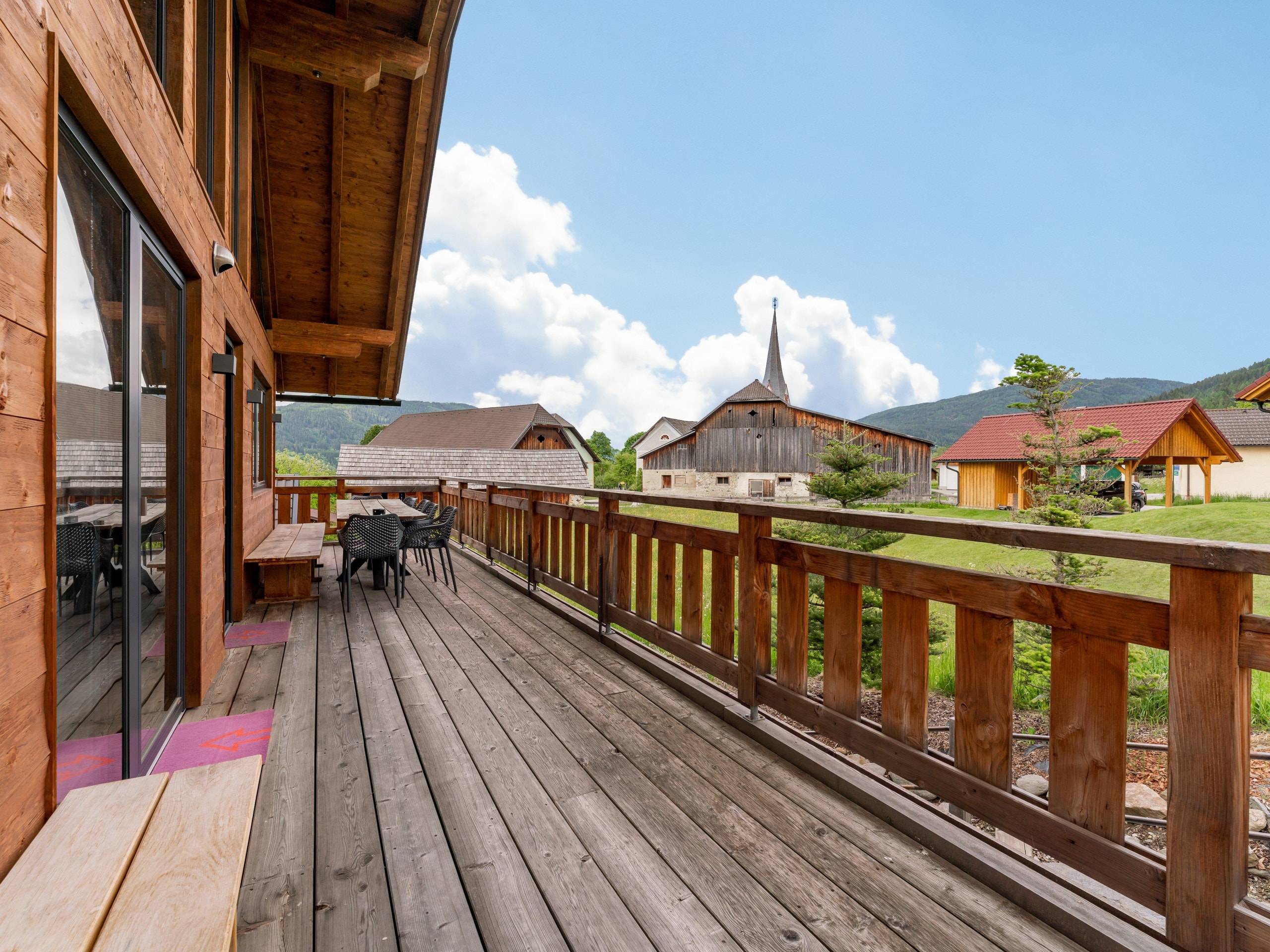 Holzterrasse von Chalet 2 mit Tisch und Blick auf das Dorf und die Berge