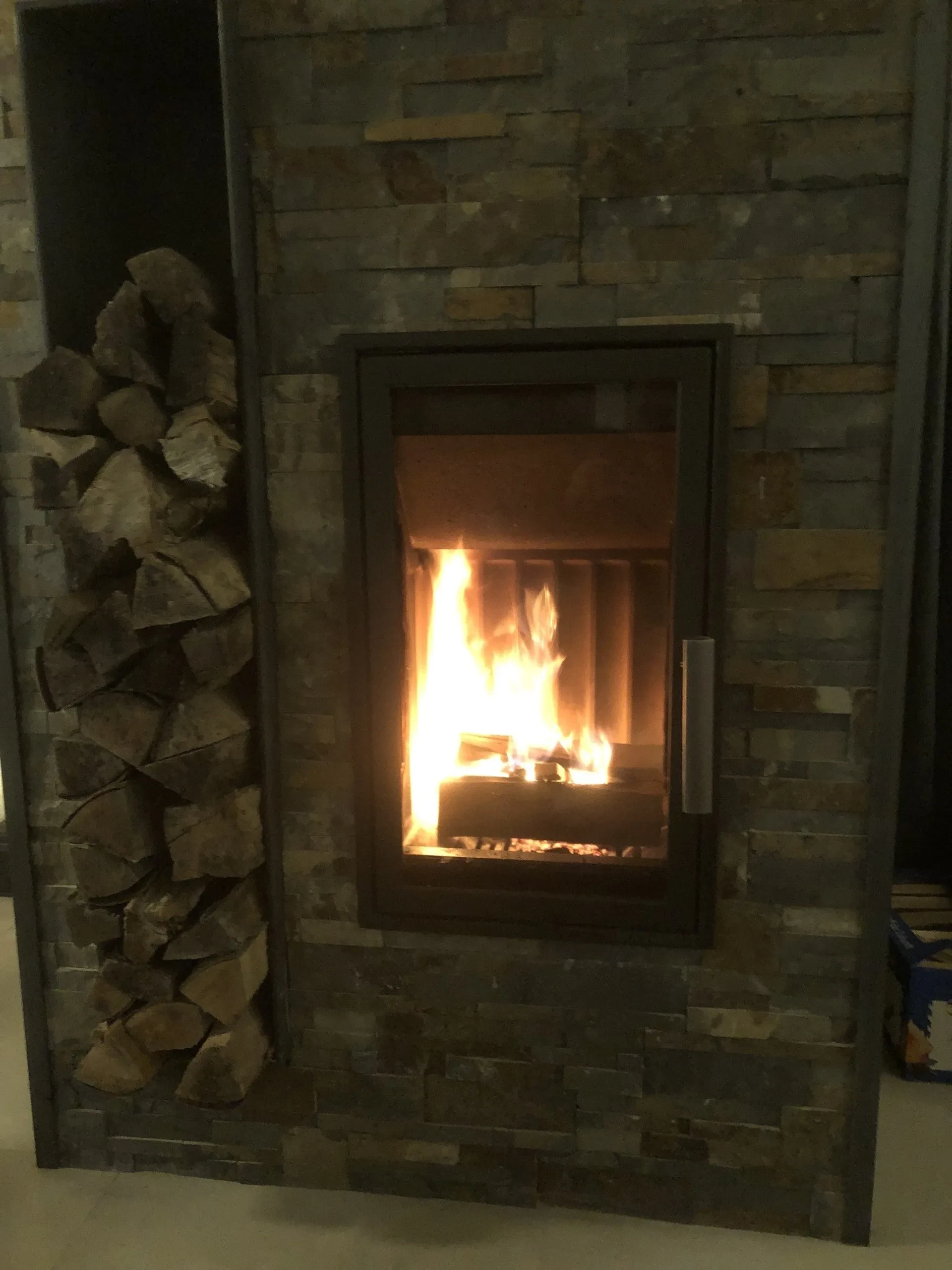 Brennender Holzkamin mit Holzlager