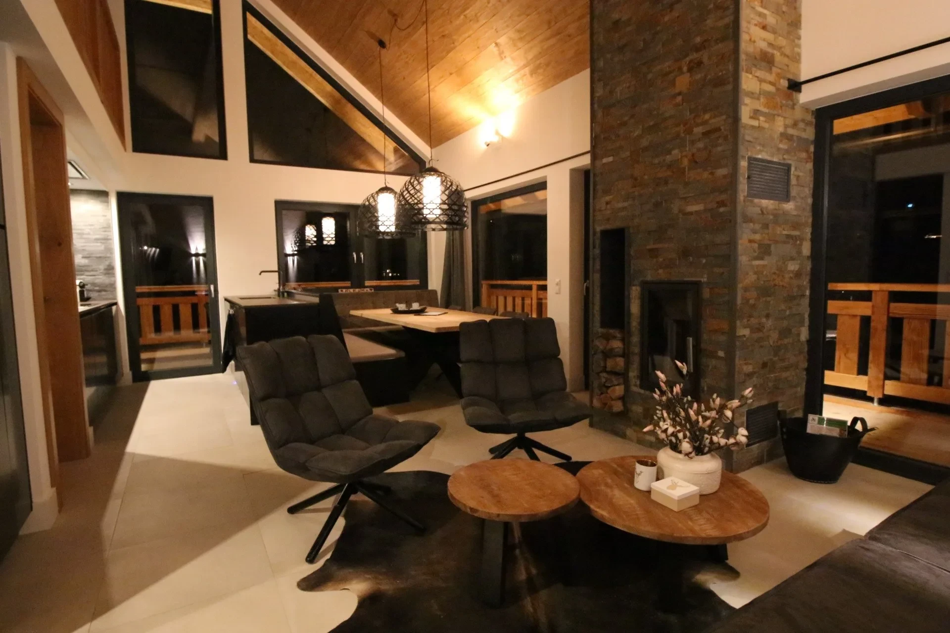Living room with high ceiling, designer armchairs and fireplace