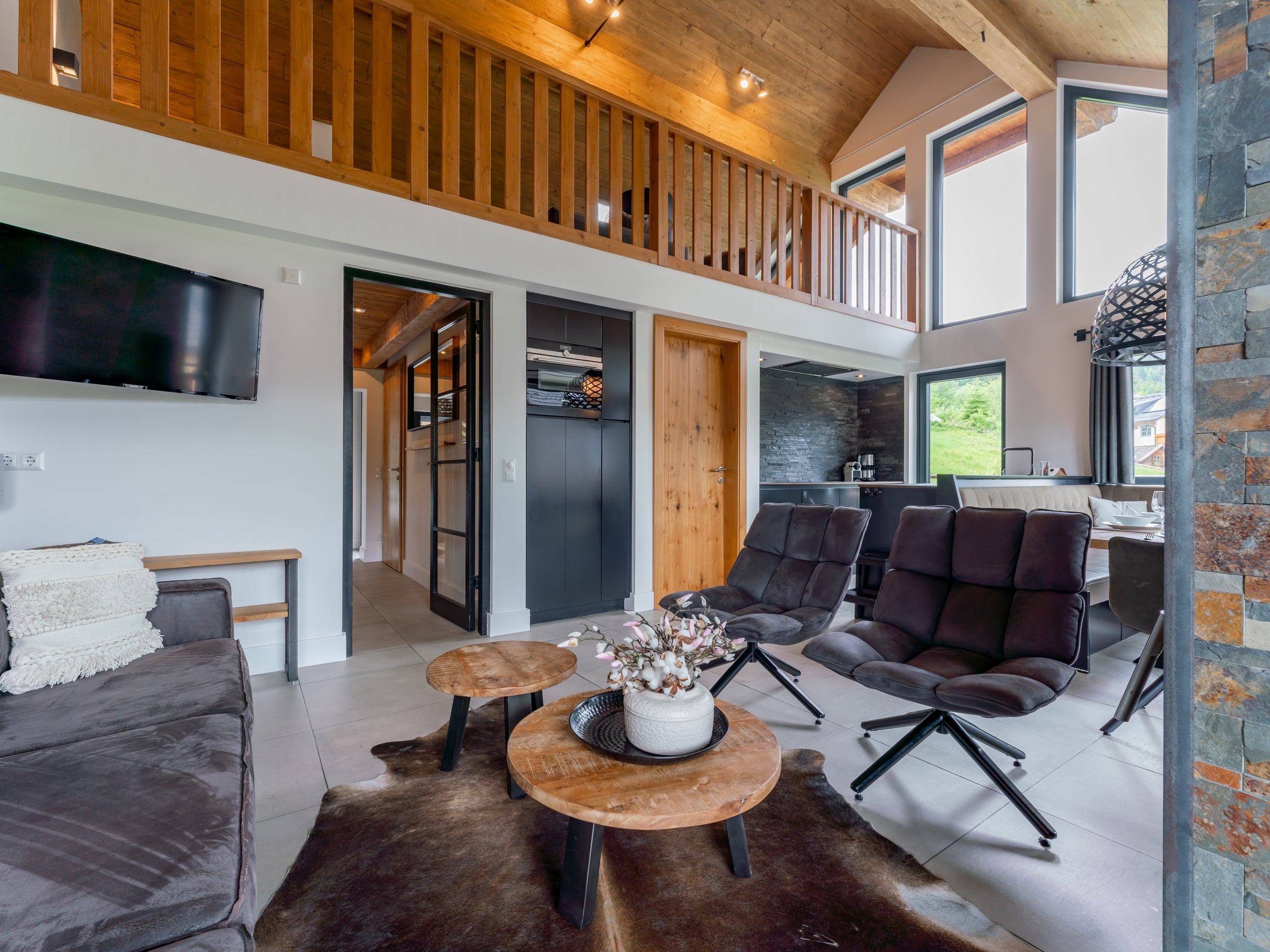 Helles Wohnzimmer von Chalet 1 mit Sesseln, Kamin und Galerie