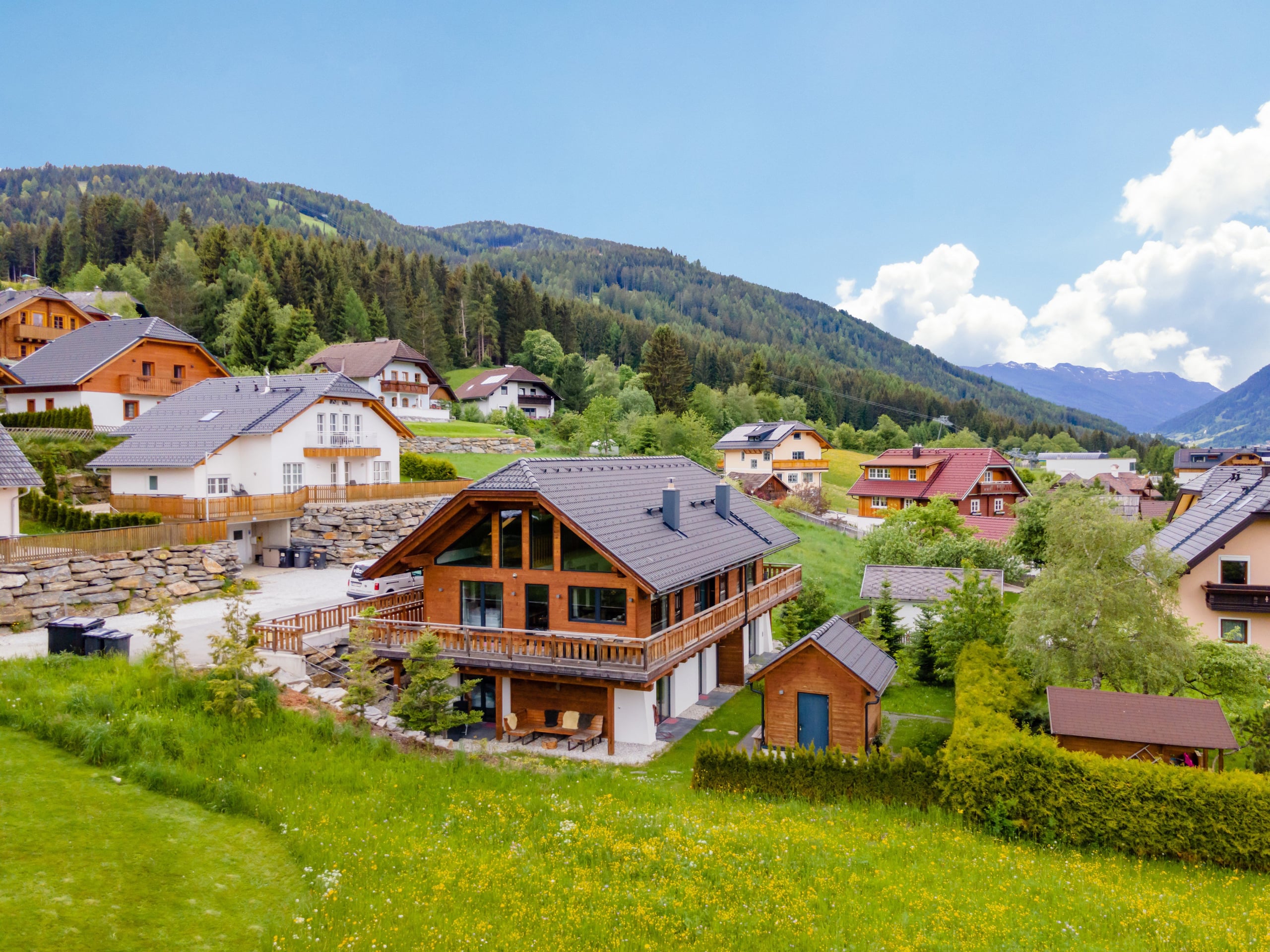 AlpInn chalet in Sankt Margarethen im Lungau with the village and mountains on a sunny day