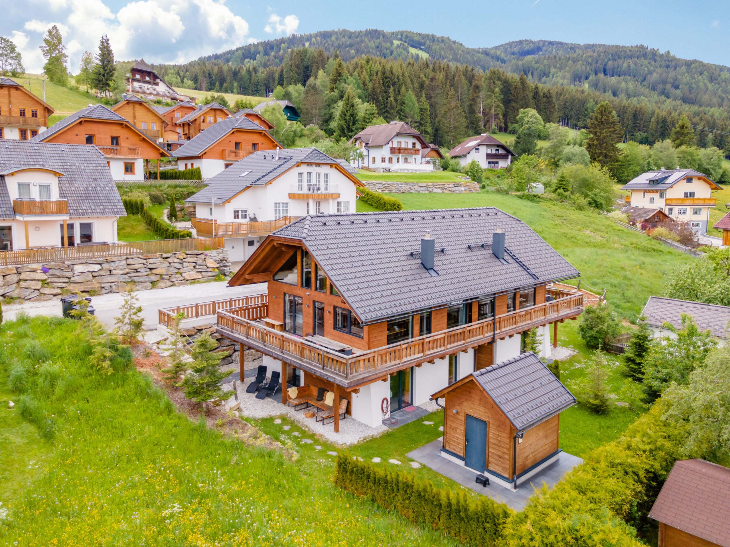 AlpInn chalet met balkons, tuin en berging, van bovenaf gezien in de zomer