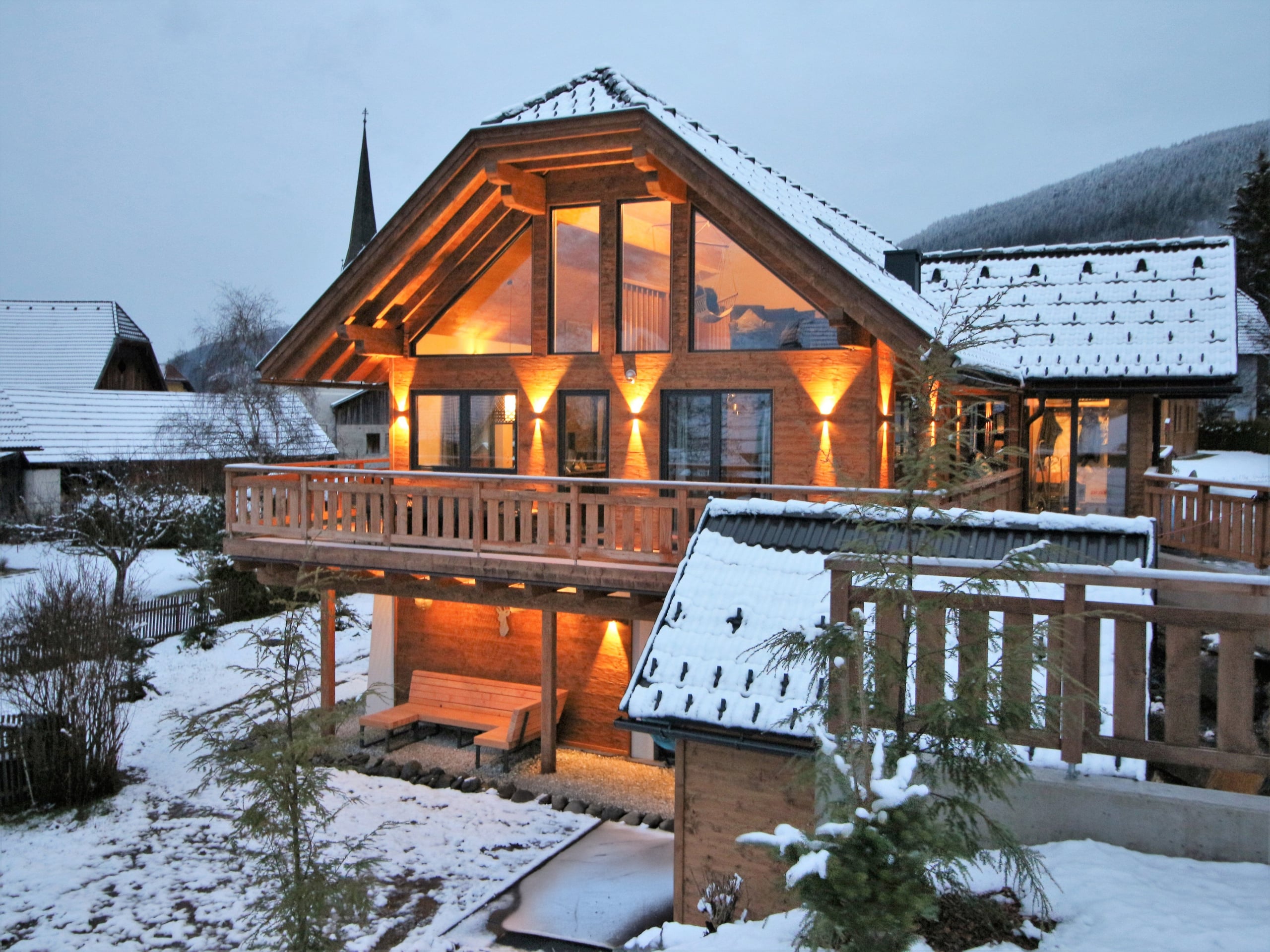 AlpInn chalet op een winteravond, met verlichte ramen en sneeuw op het dak